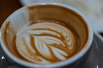 Close up a cup of hot latte art coffee on wooden table.A cappuccino is an espresso-based coffee drink with steamed milk foam.Best of menu in the coffee shop or restaurant.