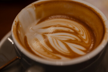 Close up a cup of hot latte art coffee on wooden table.A cappuccino is an espresso-based coffee drink with steamed milk foam.Best of menu in the coffee shop or restaurant.