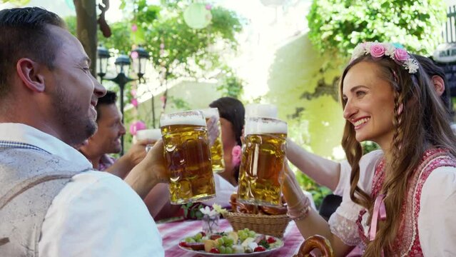 Couple looking at each other clinking glasses with huge amounts of beer in Bavarian pub
