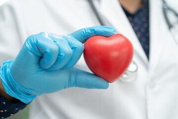 Doctor holding a red heart in hospital ward, healthy strong medical concept.