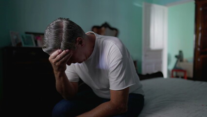 Anxious preoccupied older man sits by bedside feeling worry. Stressed desperate middle-aged person...