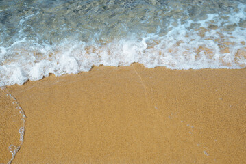 Beach close-up. Top view sea wave on the sand on a sunny summer day