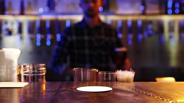 Young man, bartender in checkered shirt serving lager foamy beer in big glass for client. Visiting pub, bar for drinking. Concept of alcohol drink, party, taste, relaxation. Ad