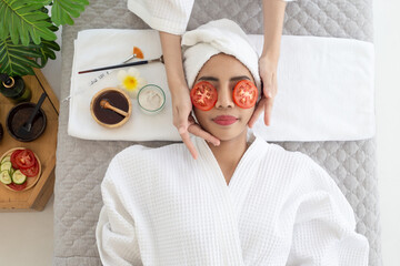 Relaxed young asian woman getting eye nature treatment by tomato at spa salon. Wellness and healing concept.