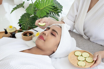 Relaxed young asian woman getting eye nature treatment by cucumber at spa salon. Wellness and healing concept.
