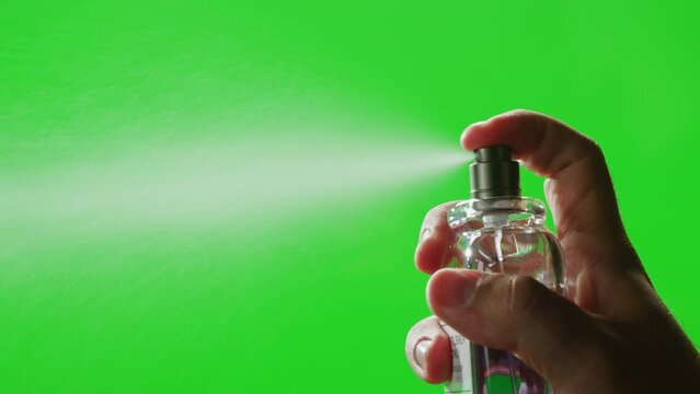 Young man applying perfume to skin on chroma key green screen, close up of spraying deodorant luxury perfume.