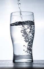 Water is poured into a glass from above
