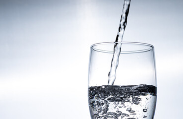 Water is poured into a glass from above