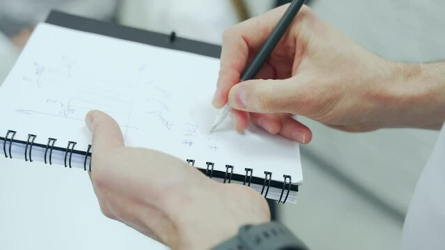businessman taking notes in a notebook, makes notes at a meeting conference or training, close up The hands of a male employee are writing on paper