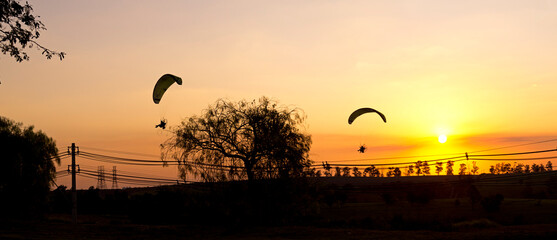 Paramotors in silhouette, flying over region of Campinas - SP, Brazil, in sunset