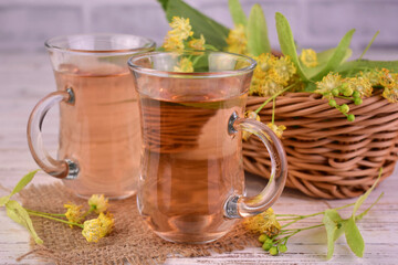 Two cups of medicinal linden tea on a white wooden background.
