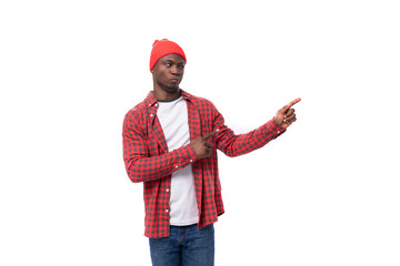 surprised positive young african man in cap and shirt telling news on isolated white background