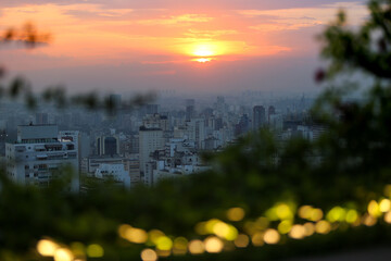 Vista aérea do pôr do sol em São Paulo: foto deslumbrante capturada da cobertura de um arranha-céu, mostrando uma ampla visão da cidade e a presença da poluição atmosférica.
