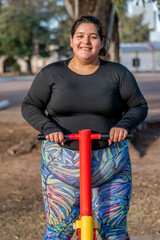 Young fat woman doing leg exercise in the park by the lake. Healthy lifestyle