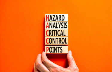 HACCP symbol. Concept words HACCP hazard analysis critical control point on wooden block. Beautiful orange background. Business HACCP hazard analysis critical control point concept. Copy space.