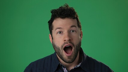 Slow motion portrait of amazed man shocked, saying WOW. Handsome hip guy with stylish hairdo surprised to camera on green screen chroma key background.