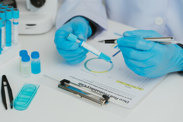 Fototapeta premium Close up view of scientist analyzing a liquid in the test tubes in laboratory.