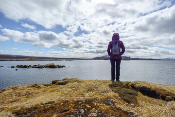 Fototapeta na wymiar woman looking at a lake in iceland by day with a beautiful landscape in the background