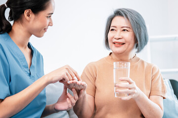 Contented senior woman taking medicines while her caregiver advising her medication. Medication for...