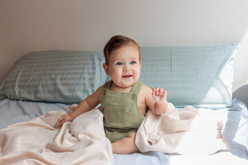 Bebé de ocho meses en su cuarto jugando sonriendo y alegre en un día de sol.