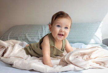 Bebé de ocho meses en su cuarto jugando sonriendo y alegre en un día de sol.