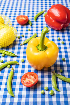 Vertical image of yellow,red bell pepper, peas, tomatoes and lemons on the blue tablecloth