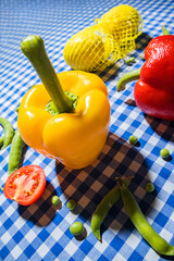 Yellow sweet pepper and other spring food on checked blue tablecloth