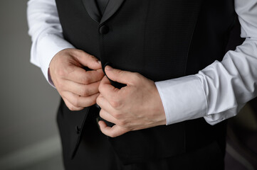 Portrait of a fashionable man fastening a button on jacket, close-up.Wedding day. Young modern businessman.