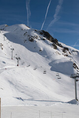Fototapeta na wymiar Ski resort in the mountains, with ski lifts, airplane vapor trails in blue sky, Les Deux Alpes, Isère, Auvergne-Rhône-Alpes, France