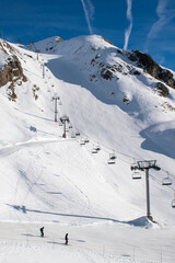 Ski resort in the mountains, with ski lifts, skiers in the foreground and airplane trails in the blue sky, Les Deux Alpes, Isère, Auvergne-Rhône-Alpes, France