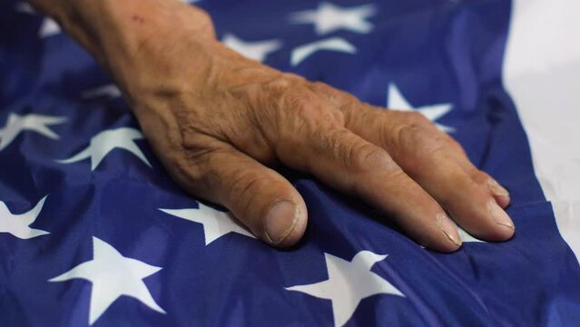 close-up of the old man's hand touches and strokes the American flag, the concept of a war veteran, feelings of patriotism, an American pensioner