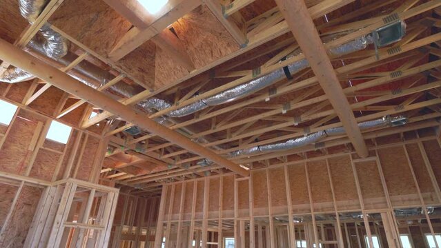 New Southwest Home Construction Interior Framing Ceiling Pull Back Sun Flare. slow motion view in home construction framing interior look up at skylight ceiling pull back reveal sun flare