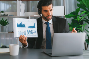 Business man wearing headphone present financial data or BI paper via laptop during online meeting. Remote work concept with virtual meeting presentation of effectiveness remote work. Fervent