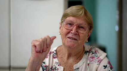 Elderly senior woman waving goodbye to camera, webcam POV concept of older person in 80s speaking...