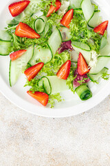 fresh salad strawberry cucumber, lettuce diet meal food snack on the table copy space food background rustic top view 