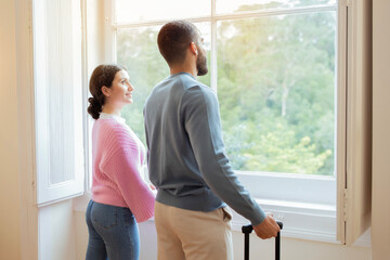 Side View Of Tourists Couple Near Window In Hotel Interior