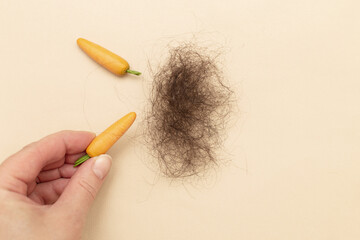 female hand holding carrot as a good product for healthy hair.