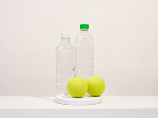 Two yellow tennis balls lying on a stand. Water in plastic bottles to quench thirst.