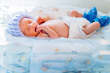 Portrait of cute premature baby boy dressed in a blue knitted wool cap sleep, Neonatal intensive...