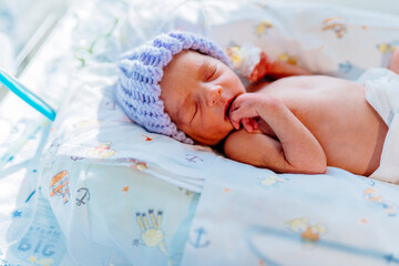 Portrait of cute premature baby boy dressed in a blue knitted wool cap sleep, Neonatal intensive care unit in hospital.