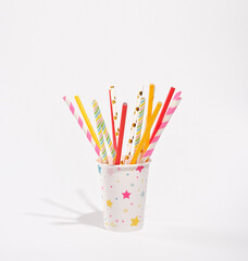 Lots of colorful, beautiful, creative straws for cocktails and other alcoholic holiday drinks stand in a paper cup.