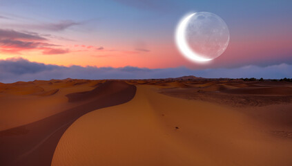 Beautiful sand dunes in orange desert at sunrise with crescent moon - Sahara, Morocco 