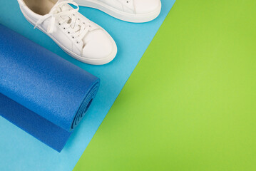 The concept of sports accessories. Photo of blue dumbbells and a blue exercise mat, white sneakers and other sports equipment.
