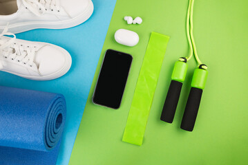The concept of sports accessories. Photo of blue dumbbells and a blue exercise mat, white sneakers and other sports equipment.