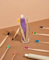 Ecological toothbrushes with colorful bristles scattered on the table. Two toothbrushes and toothpaste in a glass.