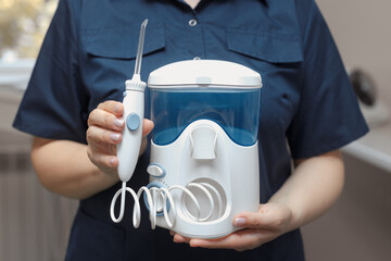 The dentist holds in hands a water oral irrigator for cleaning and hygiene of the dental cavity. No...