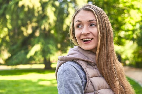 Middle-aged woman in a park on a sunny day joyful and carefree showing a peace symbol with fingers.