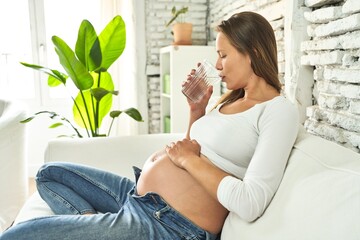Pregnant woman, sofa, water: serene rejuvenation.