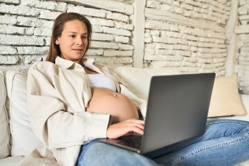 Pregnant woman, serene morning with laptop on sofa