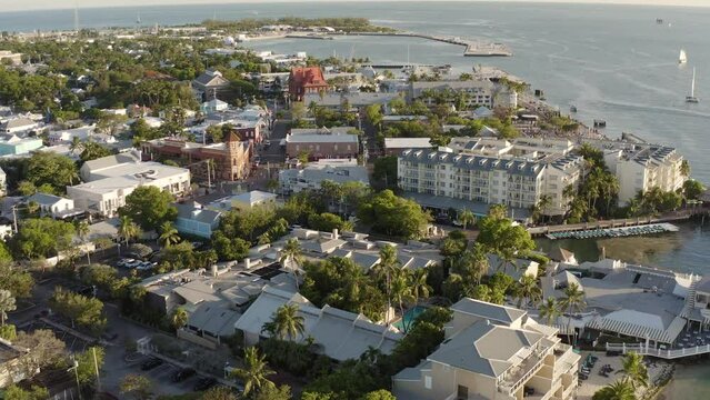 Aerial view of Key West, Florida landscape cityscape with Mallory Square and hotels, restaurants, and businesses with fishing boat in the harbor during golden hour sunset - 4K Drone 